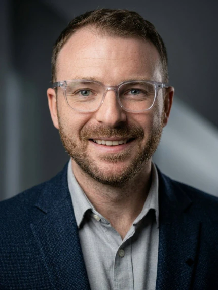 Michael Carrico smiling, wearing glasses and a navy jacket.